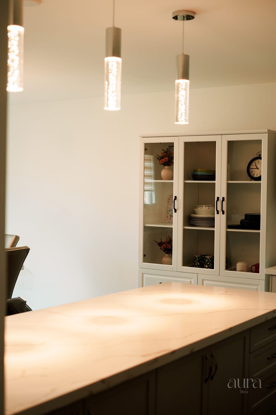 A bright kitchen with pendant lights and glass-front cabinets