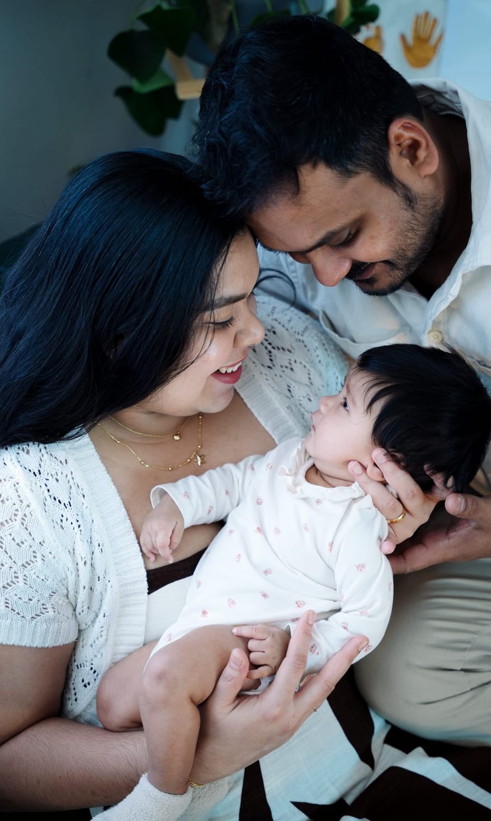A mother laughs down at her newborn while the father cradles the baby