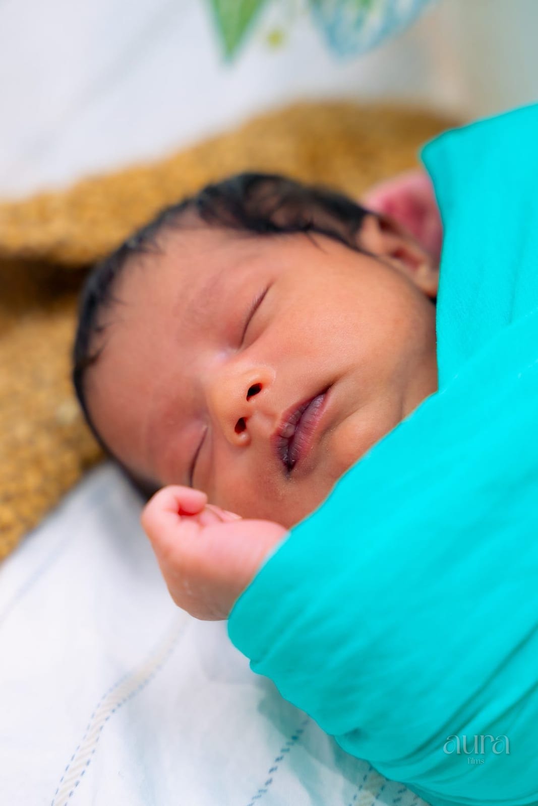 A sleeping newborn wrapped in a turquoise blanket