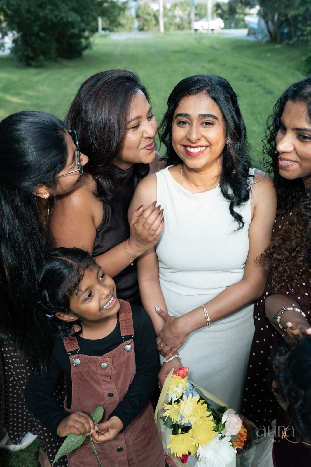 A bride laughs with her bridesmaids in a garden